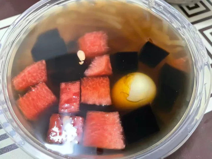 A clear qingbuliang with watermelon, dark jelly and a quail egg
