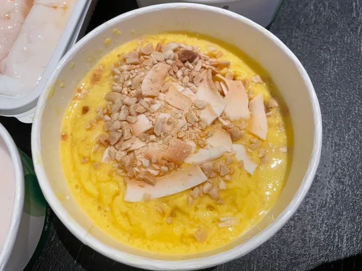 Mango milk stir-fried ice qingbuliang topped with crushed peanuts and coconut pieces
