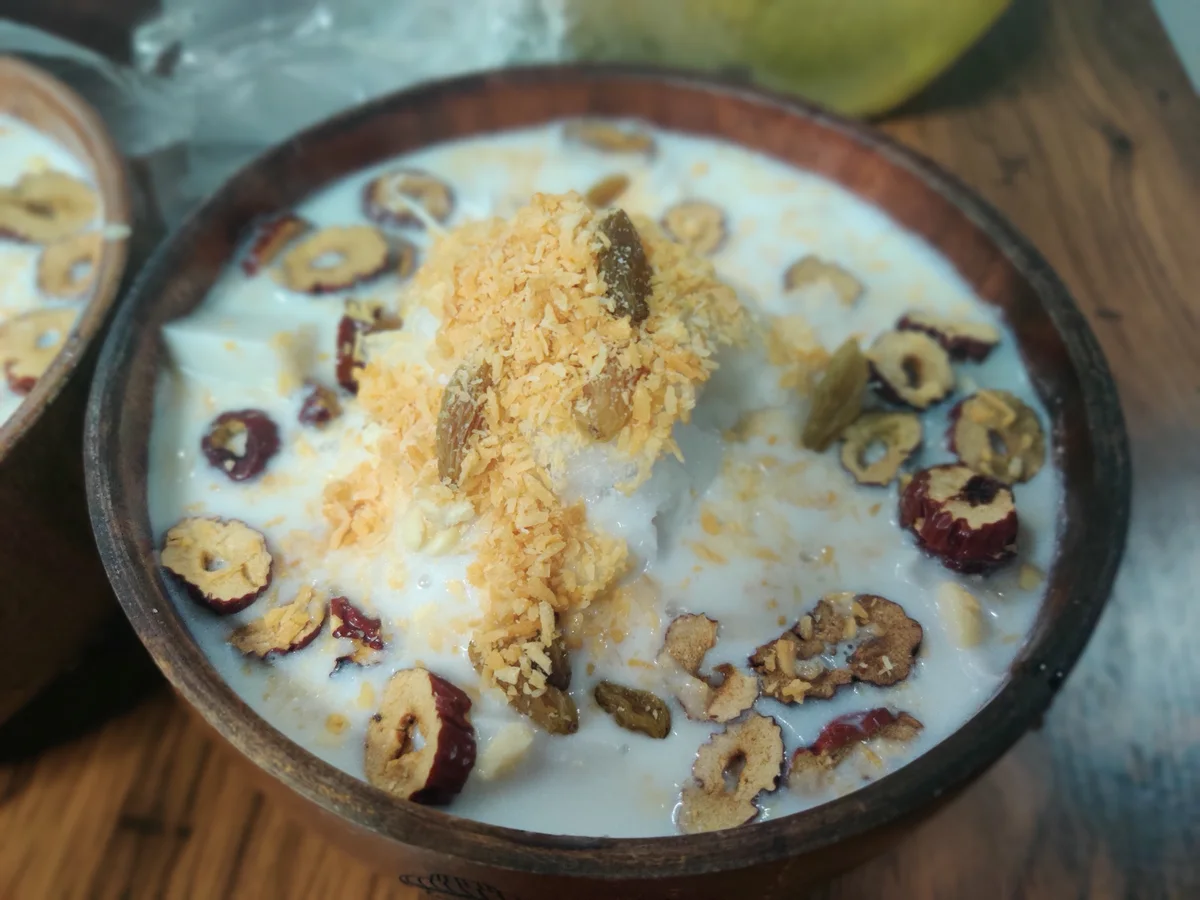 A bowl of Hainan qingbuliang with coconut milk, crushed ice, red dates and mixed toppings