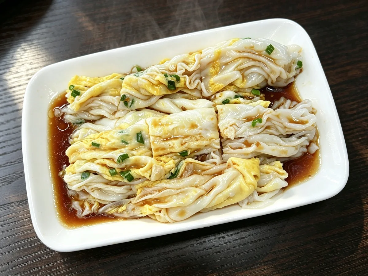 Steamed Cantonese rice noodle rolls served on a plate with soy sauce